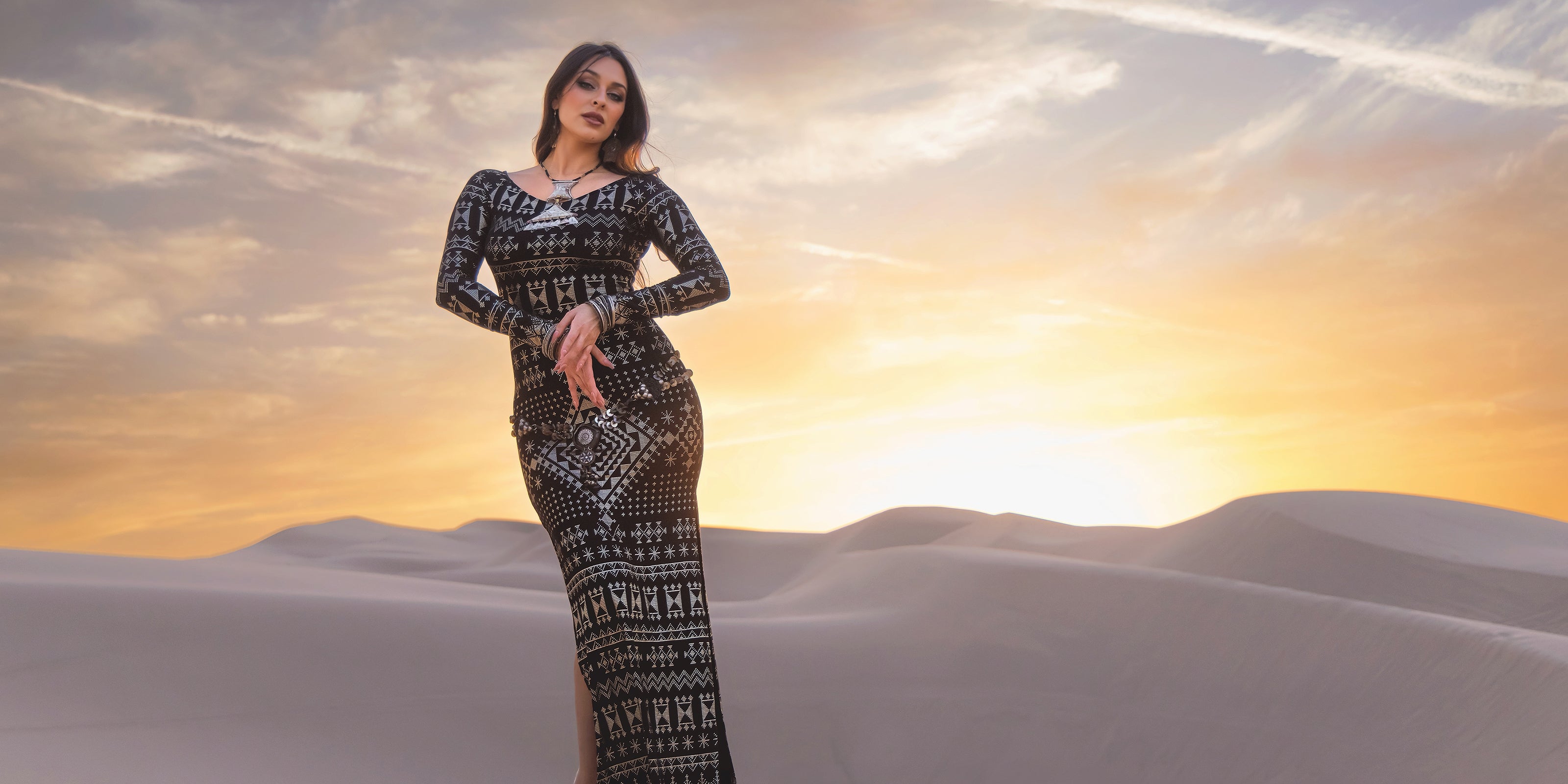 Woman in a patterned dress from Melodia Designs standing in a desert with a sunset sky
