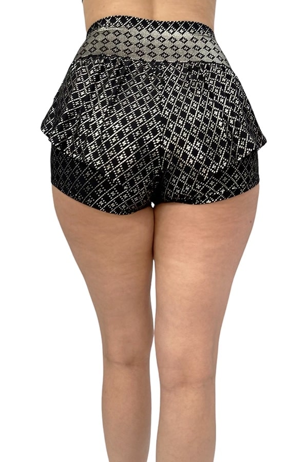 A person is shown from the back wearing Melodia Designs Angela Ruffle Short, a high-waisted black peplum-style short with a shiny silver geometric pattern, standing against a plain white background.