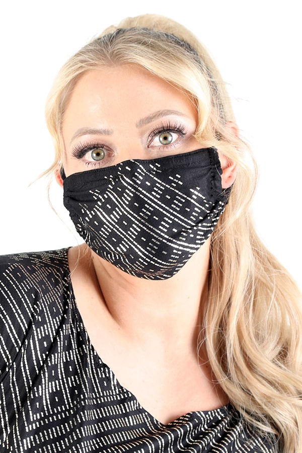 A woman with long blonde hair and bold eye makeup wears the Melodia Designs Festival Mask HM1 and a matching black and white top, posing against a plain white background.