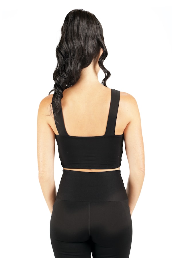 A woman with long wavy dark hair models the Melodia Designs Neisha Bra, facing away from the camera against a white background.