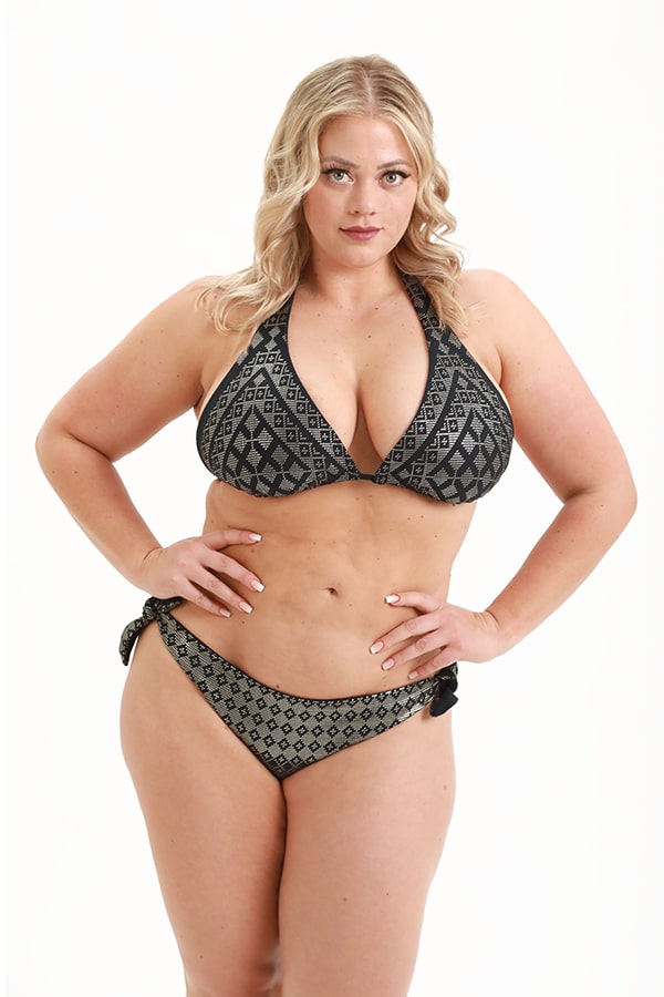 A woman with long blonde hair models the Melodia Designs Tanya Tie Side Hipster Bikini Bottom, which is adjustable and reversible in a patterned black and gray, standing confidently against a plain white background.