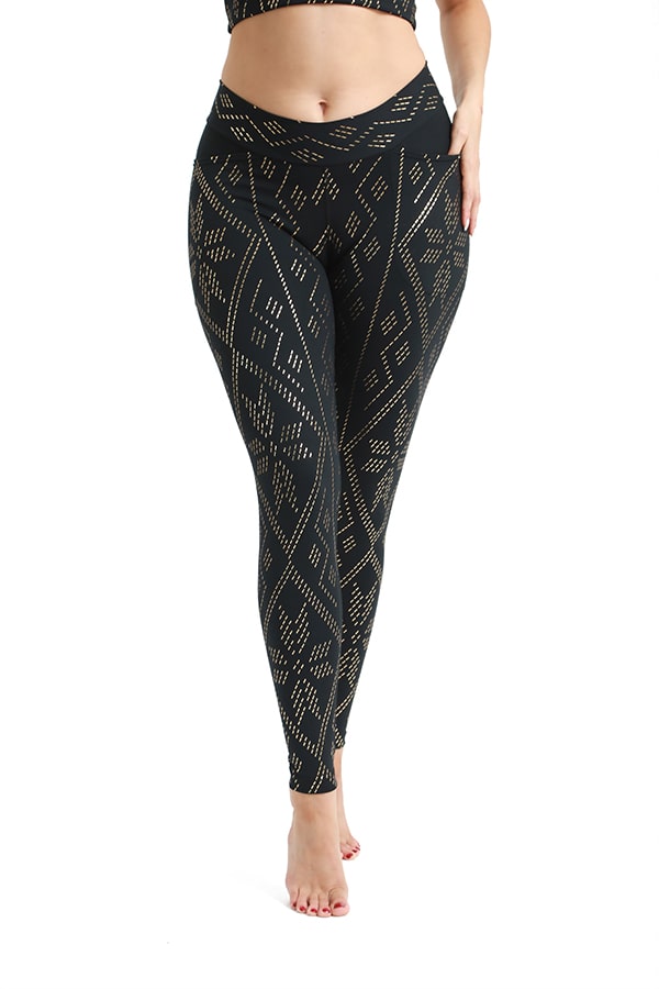 A person stands barefoot wearing Melodia Designs’ Zoe Luxor Pocket Legging—full-length black leggings with a gold geometric pattern and deep side pockets. The photo, cropped from mid-torso to feet, is set against a white background.