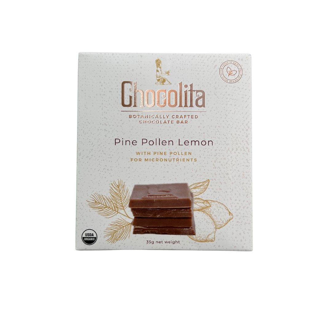 A white box of chocolita.com POWER- Pine Pollen & Lemon raw white chocolate, decorated with chocolate squares, botanical illustrations, and text highlighting pine pollen as a superfood bar. USDA organic and other certification symbols are shown.