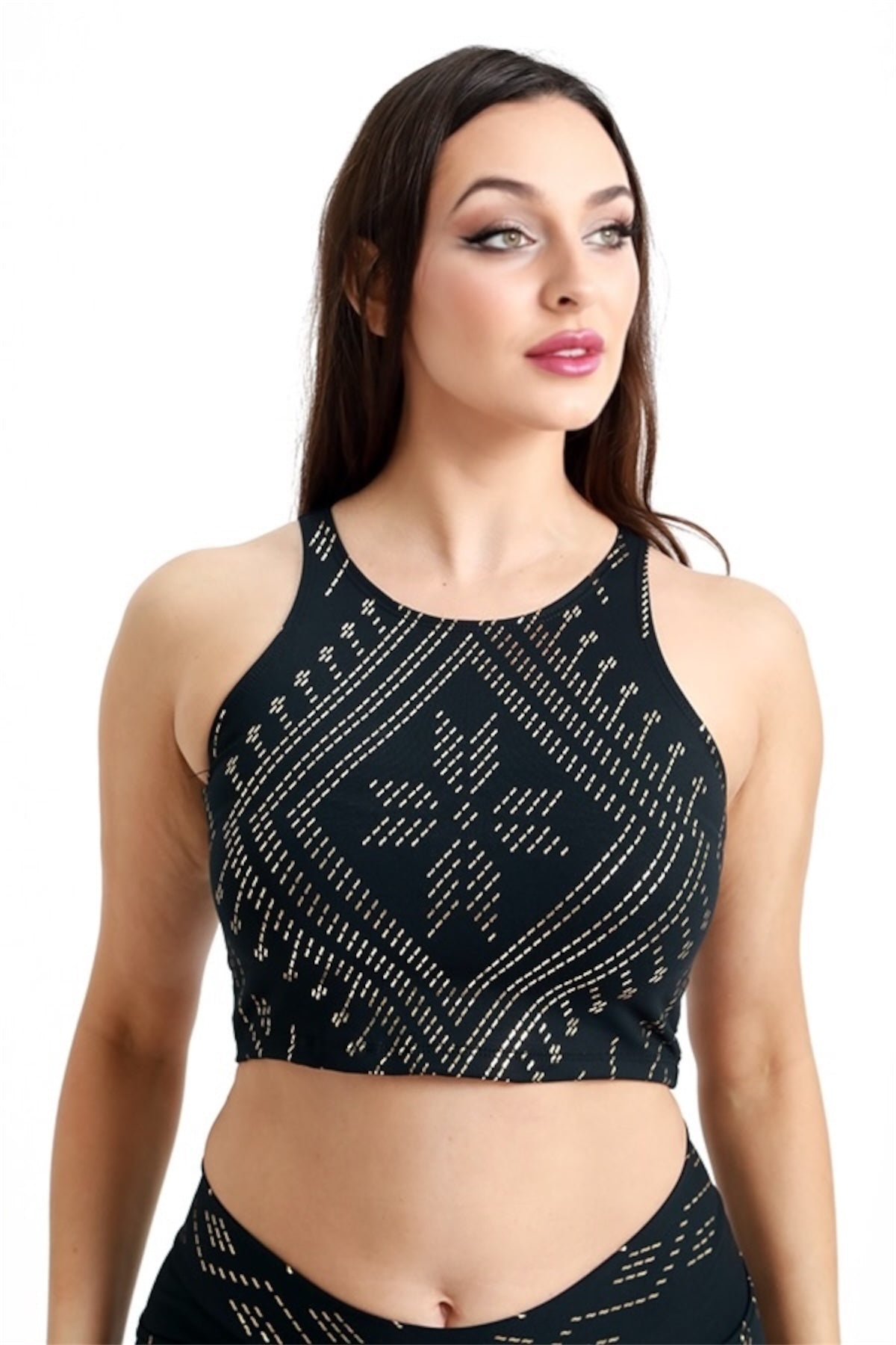 A woman with long brown hair models the Melodia Designs Laura Crop Luxor, featuring a geometric gold pattern, as she looks to the side with a neutral expression against a plain white background.